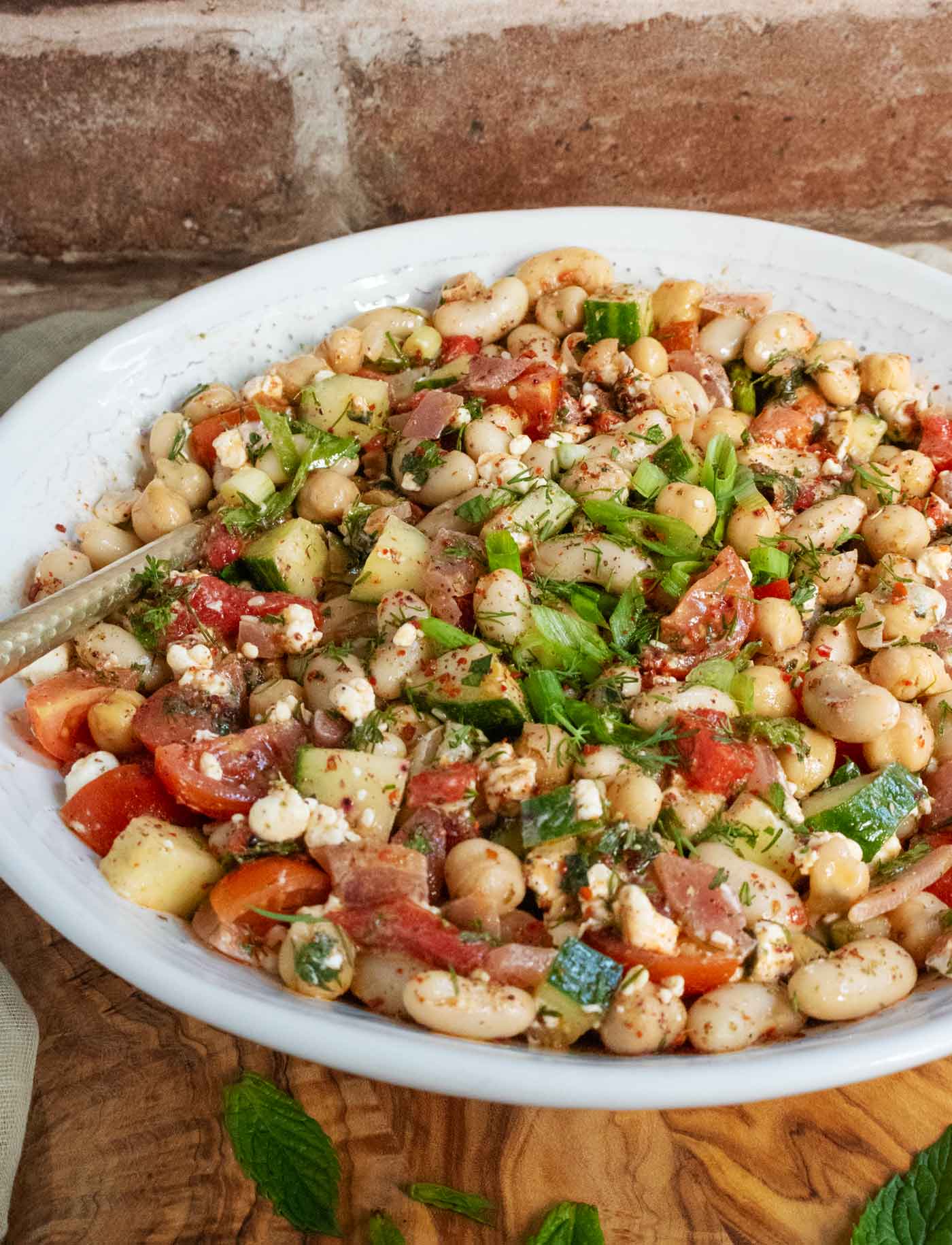 Side-angled view of the bean salad, with a gold-toned serving spoon.