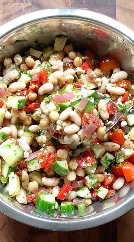 The finished bean salad, ready to serve, shown in the bowl with a spoonful slighted lifted.