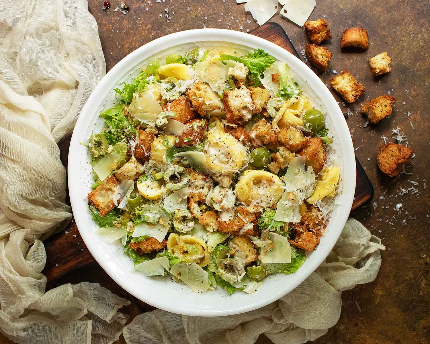Over head view of Tortellini Caesar Salad on a large white serving bowl.
