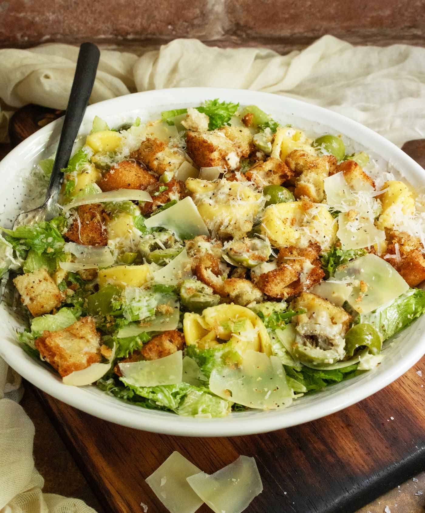 Side-angled view of the Tortellini Caesar Salad in a white serving bowl.