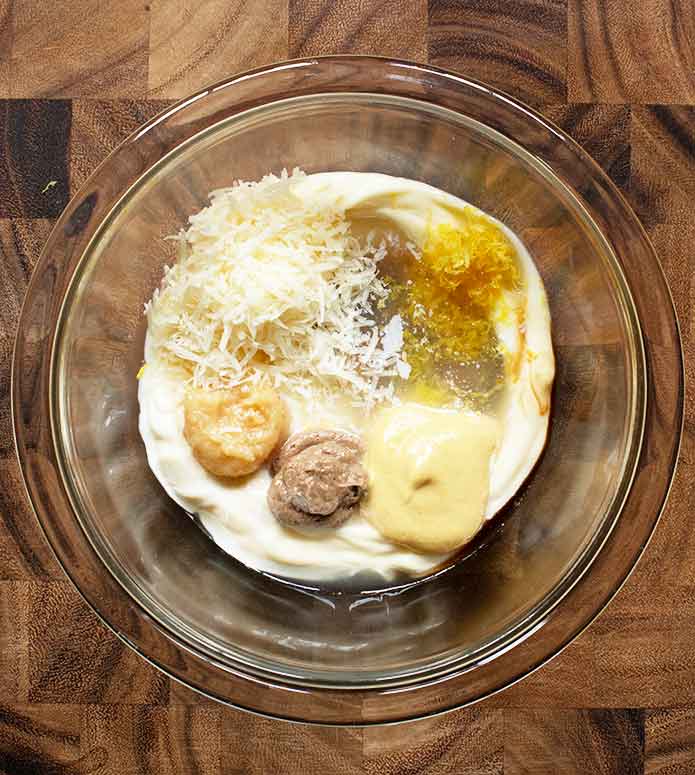 Ingredients for Easy Caesar Dressing in a glass mixing bowl.