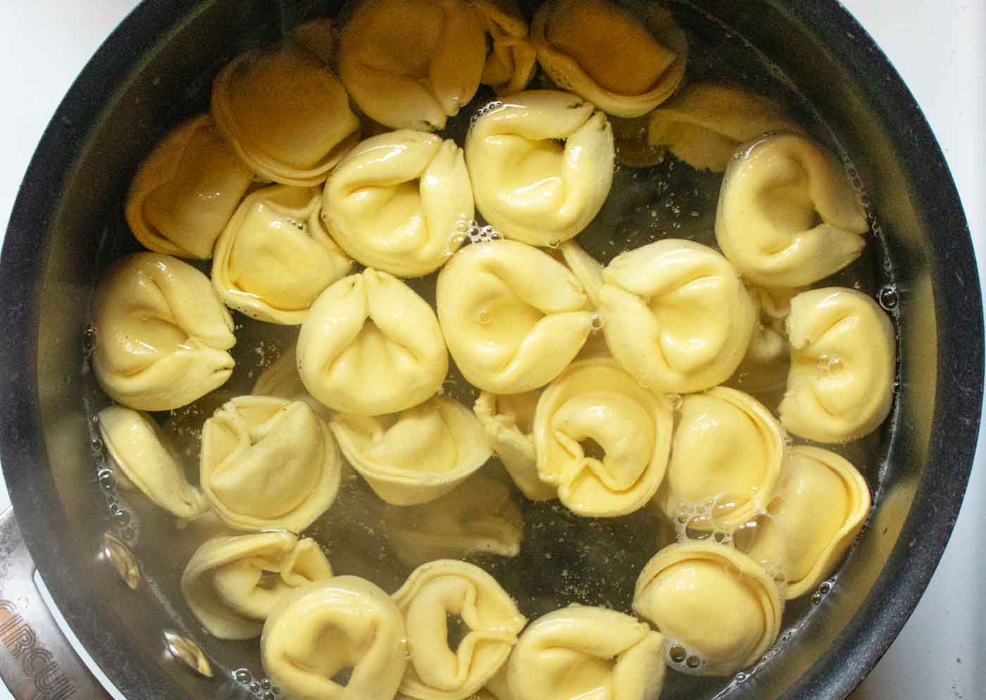 Tortellini cooking in a pot.