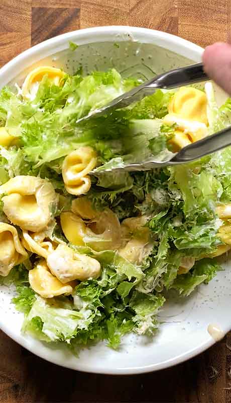 Adding the tortellini to the salad.