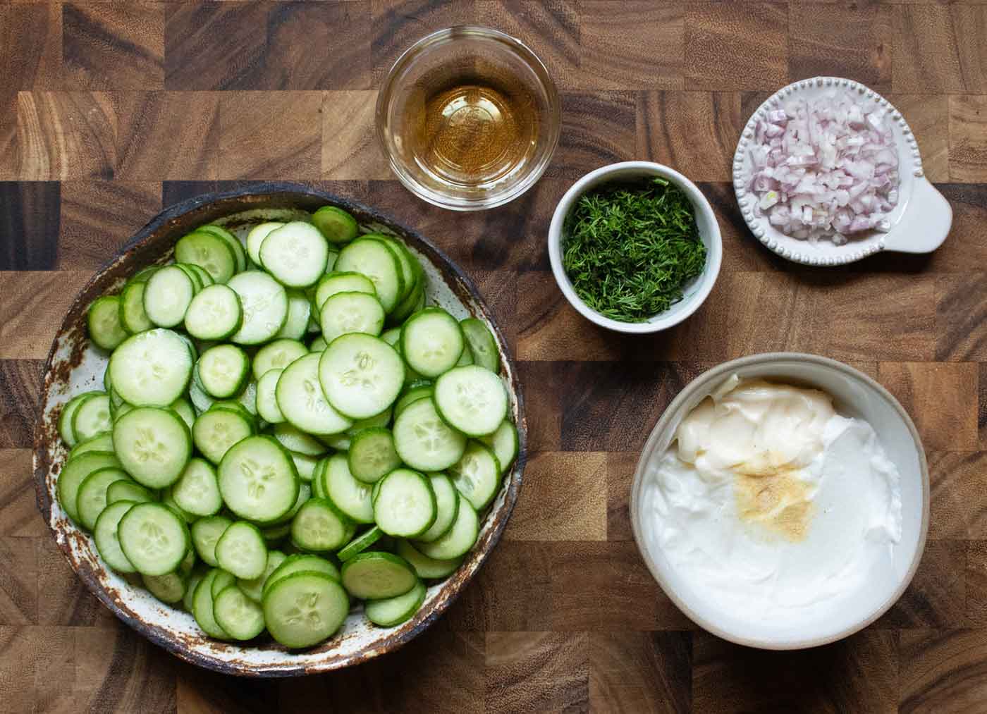 Ingredients for the cucumber salad, prepped and arranged in bowls.