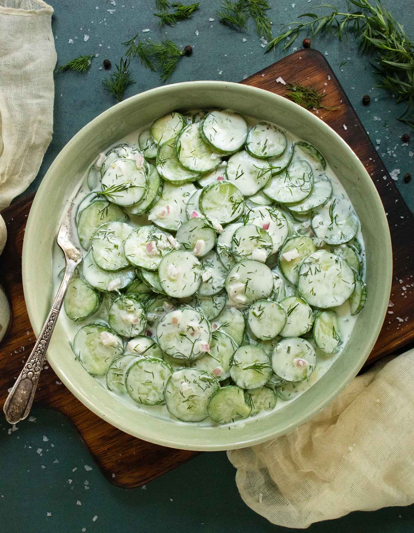 Creamy Tzatziki Cucumber Salad in a light green serving bowl with a fork.