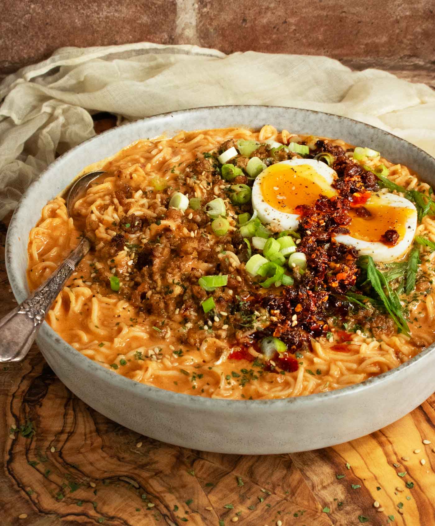 Side angled view of a bowl of Spicy Peanut Chili Crisp Ramen Noodle Soup.